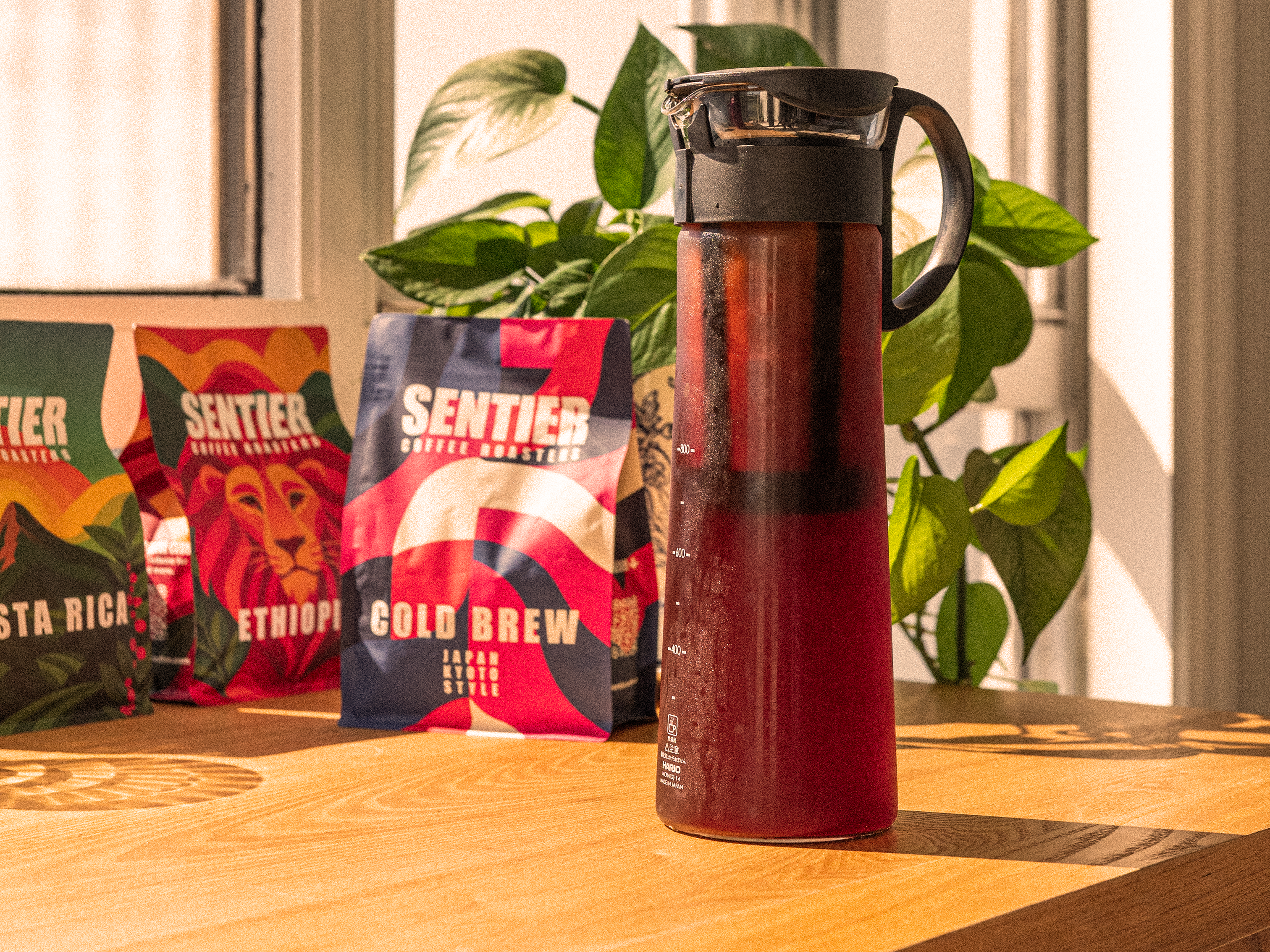 cold brew coffee maker with Sentier Coffee Company bags on a wooden surface
